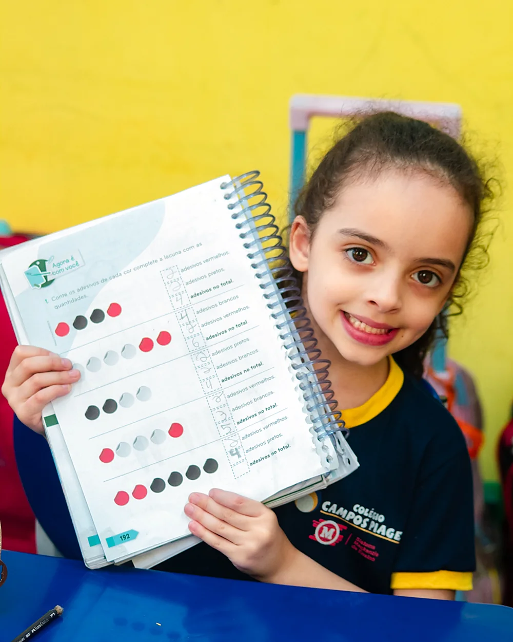 Estudante do Fundamental I mostrando o caderno de atividades
